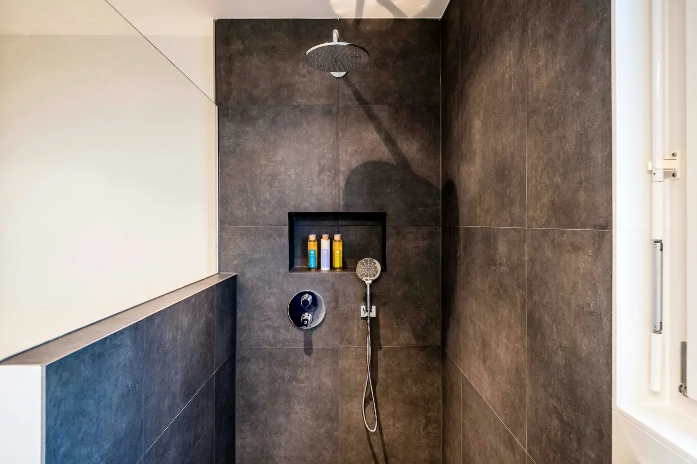 A finished shower in large concrete-look porcelain with a recessed niche